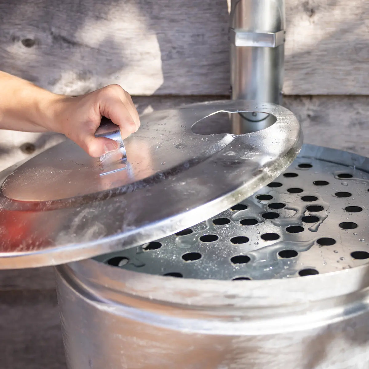 Zinken regenton met ronde opening en metalen zeefplaat met gaten