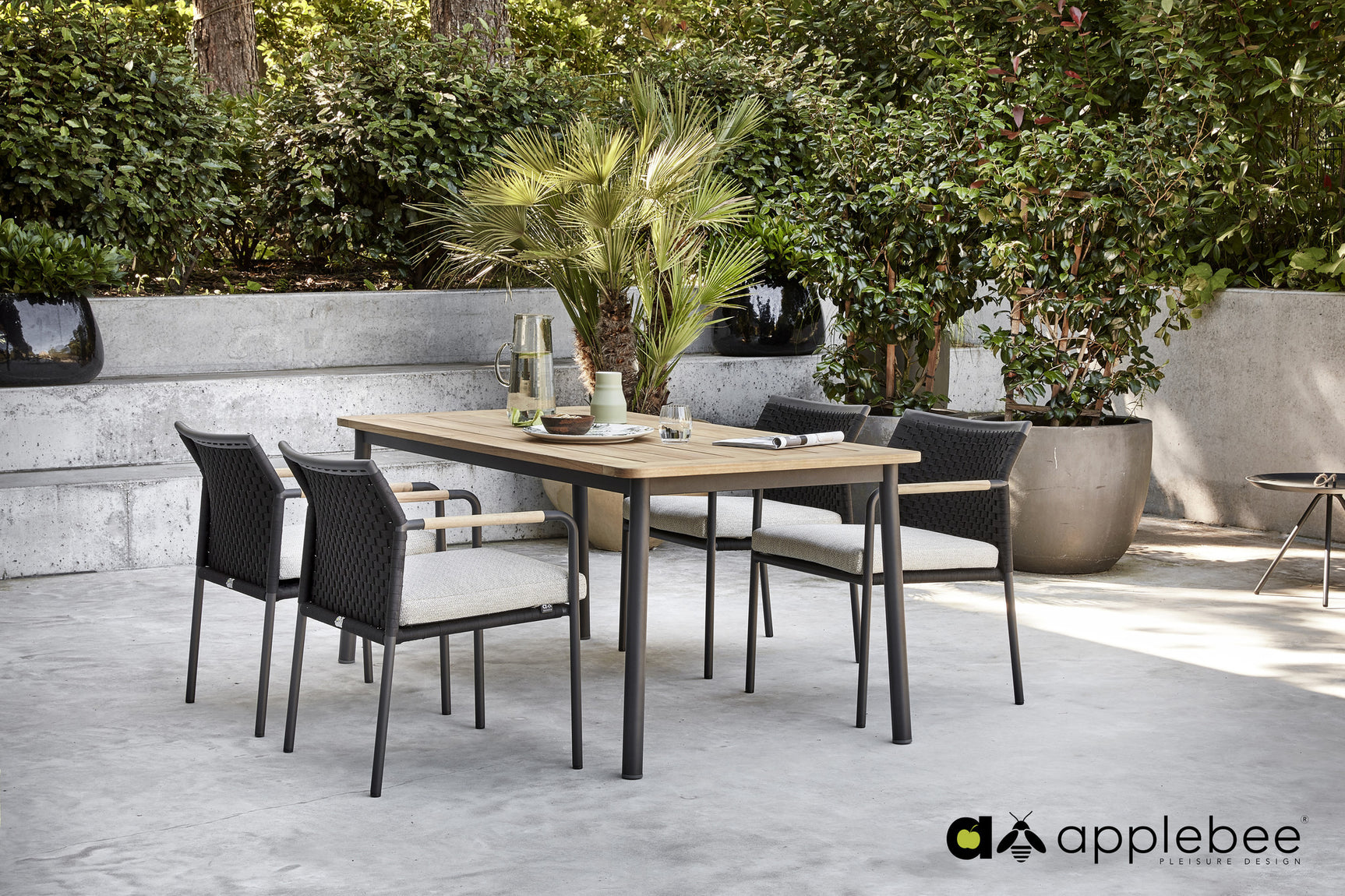 Apple Bee eettafel met houten blad en zwarte diningstoelen, buitenopstelling