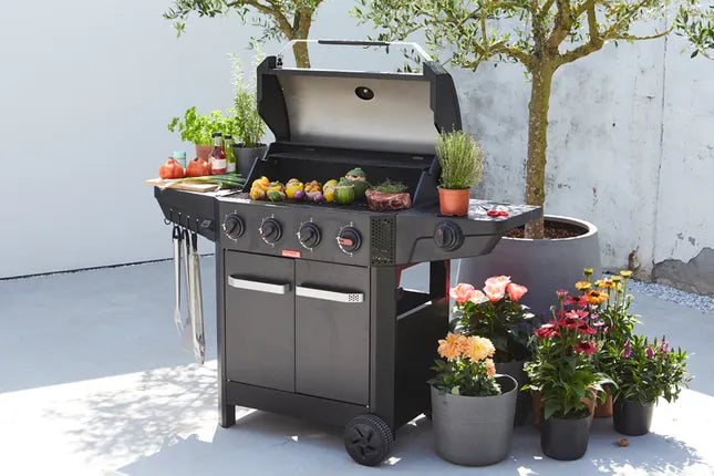 Zwart gasbarbecue met open deksel, keukengerei en schotels op het grillrek