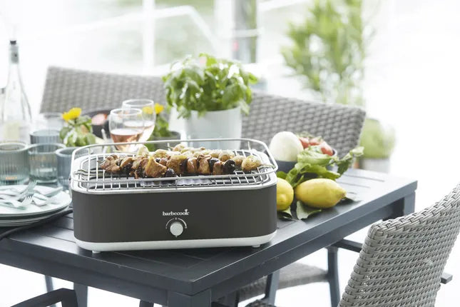 Elektrische tafelgrill met rooster vol gegrilde stukjes vlees, donkergrijze kast