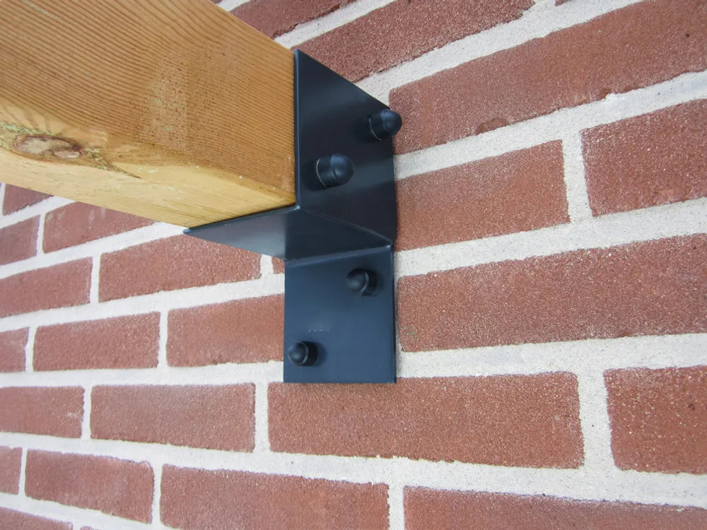 Gemonteerde zwarte wandsteunbeugels voor pergola op bakstenen muur