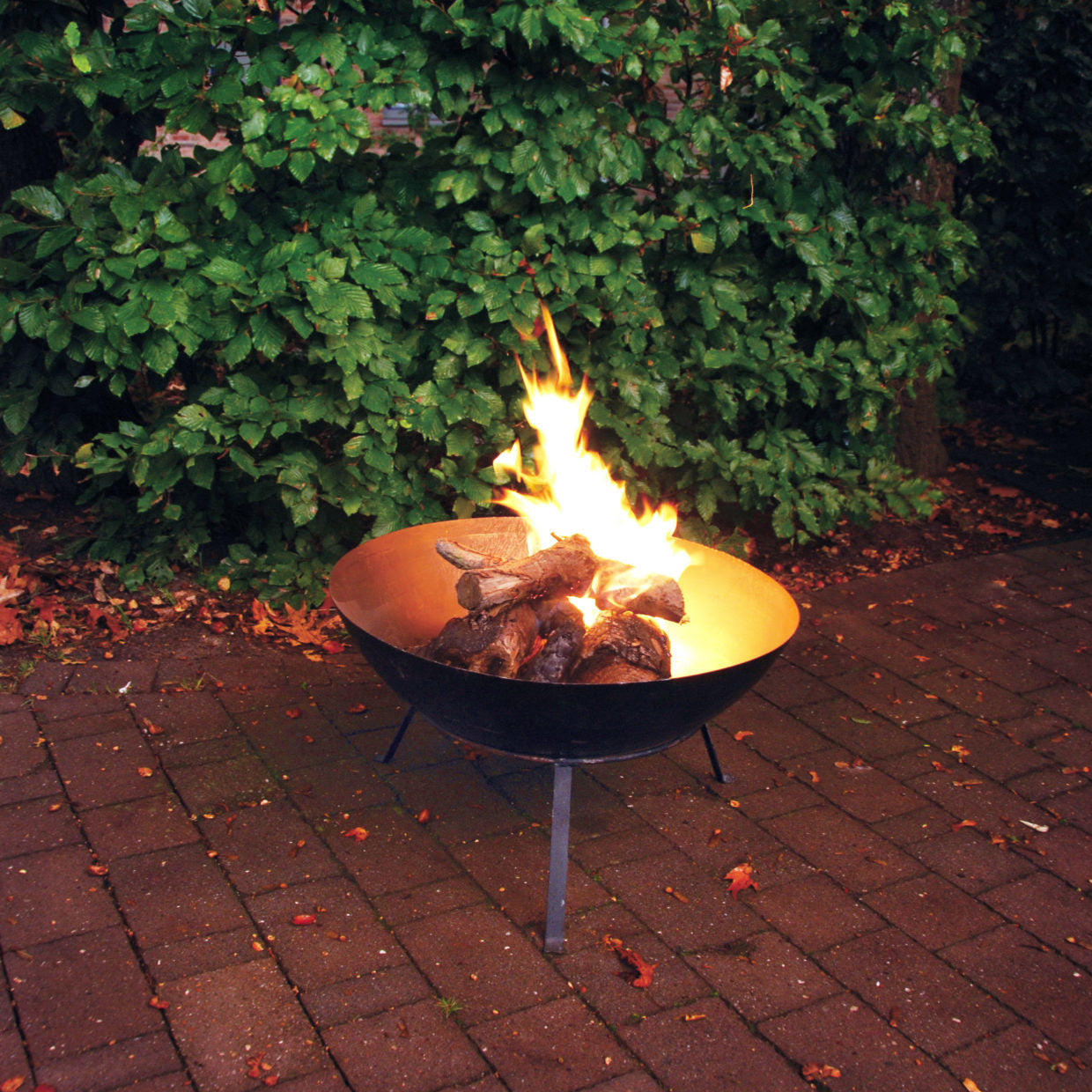Zwarte vuurschaal op drie poten met brandend vuur en hout