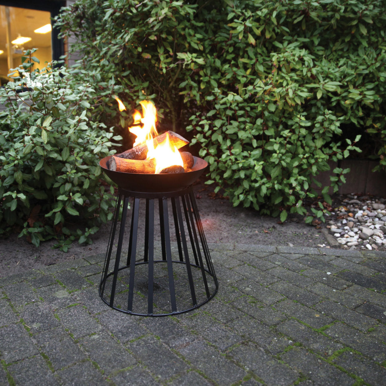 Vuurschaal met open draadkorf en brandende vlammen met houtblokken