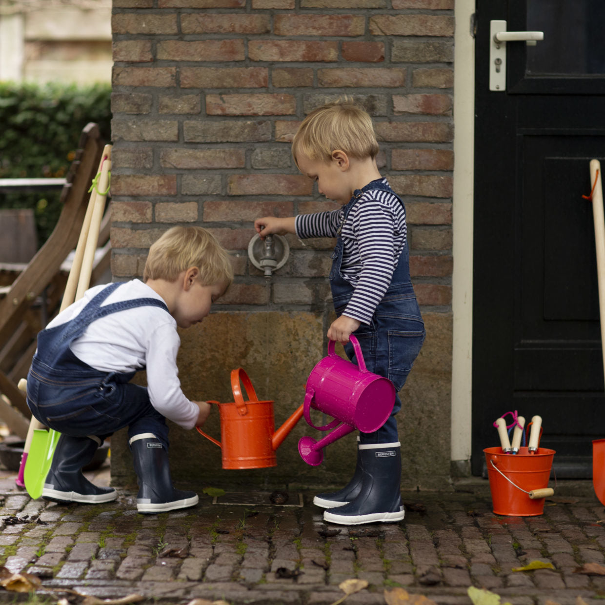 Kinder scheppen: oranje en roze schoppen met houten steel in emmers.