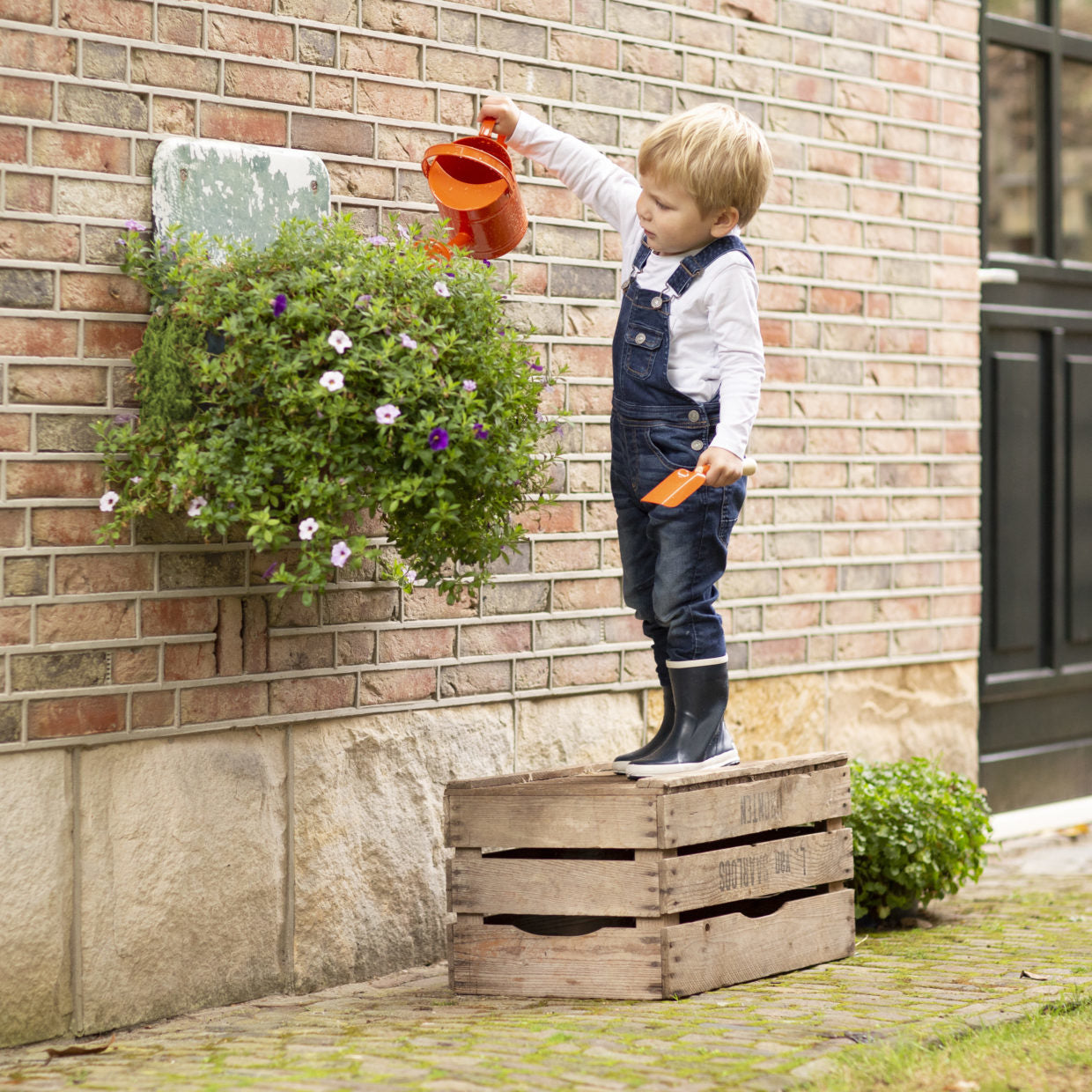 Oranje kindergieter met lange tuit, vastgehouden door een kind.