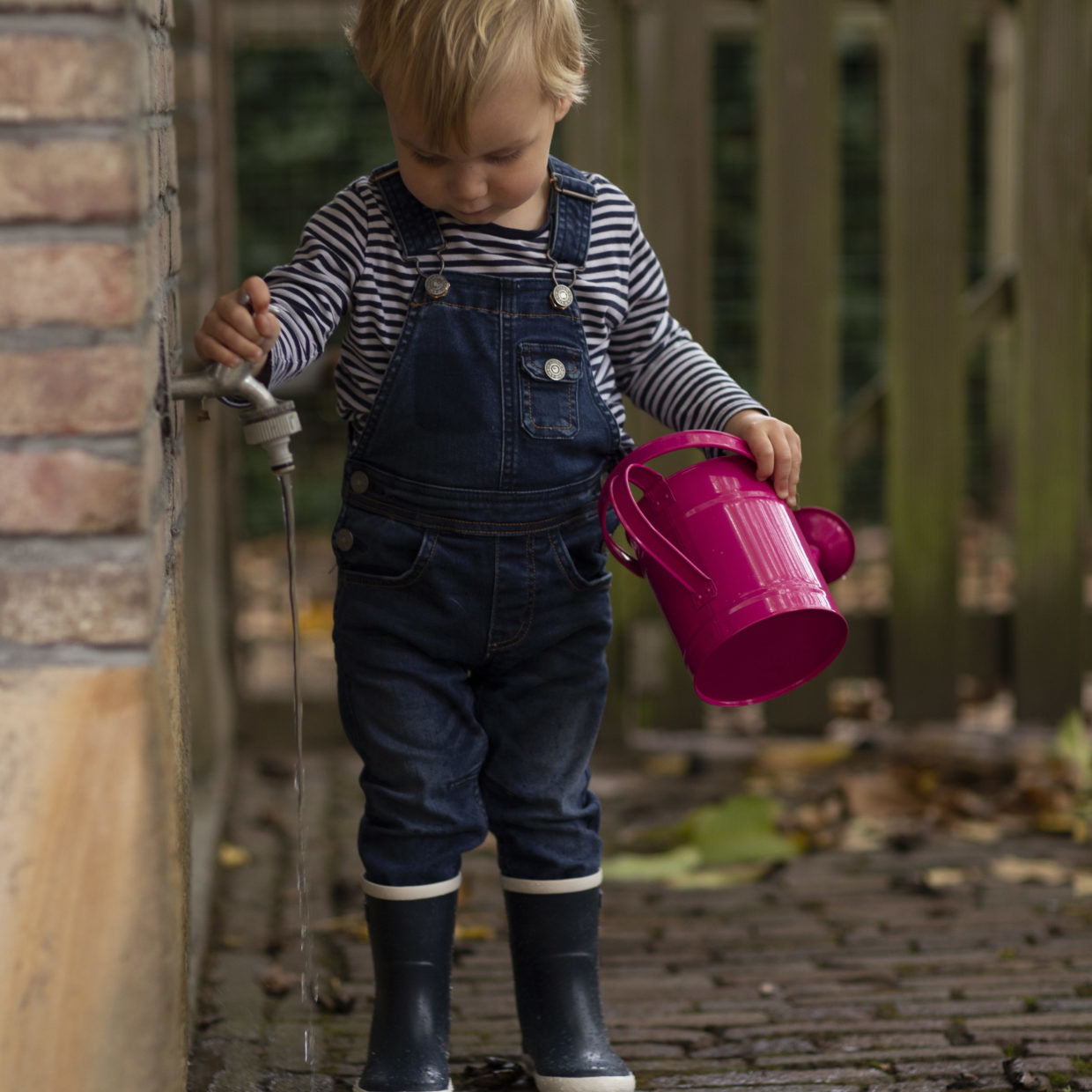 Roze kindergieter met lange tuit, vastgehouden door een kind.