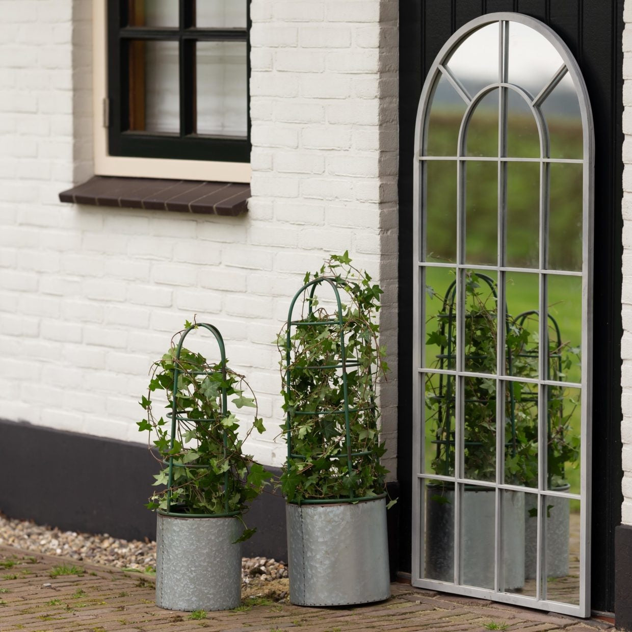 Twee grijze bloembakken met plantensteun en groene klimplanten in potten