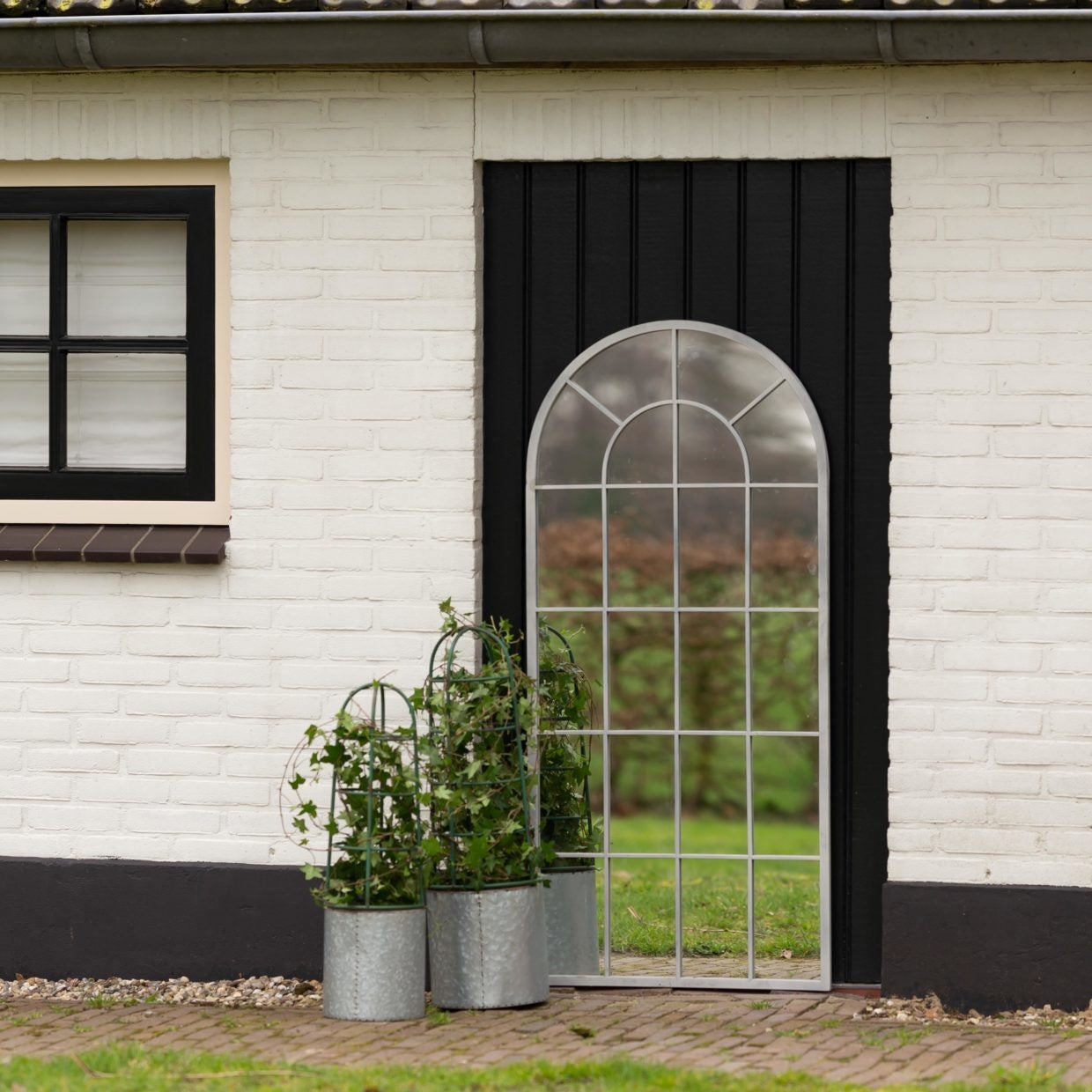 Twee grijze bloempotten met boogvormige plantensteun en groene sierplant