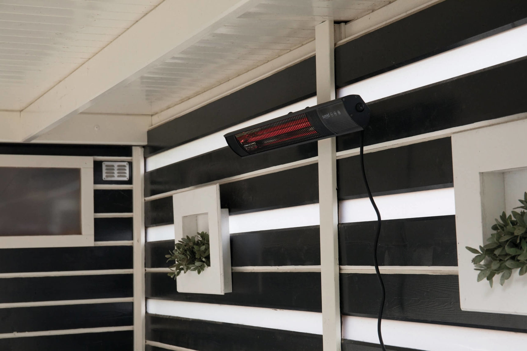 Elektrische terrasverwarmer gemonteerd onder dak met rood verwarmingsrooster