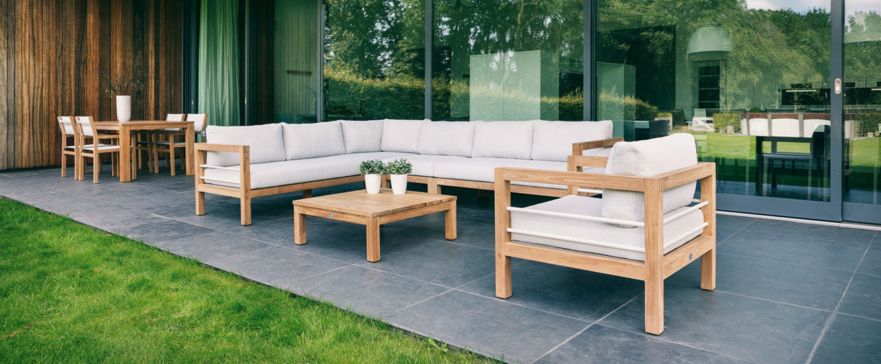 Lounge set buiten: hoekbank, twee stoelen en salontafel met lichtgrijze kussens