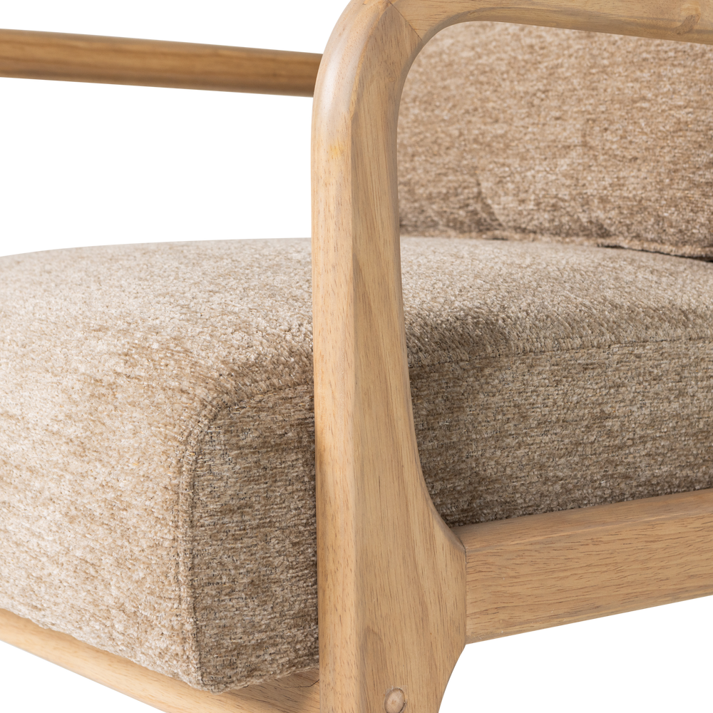 Zandkleurige chenille fauteuil met houten armleuning en volumineus zitkussen.