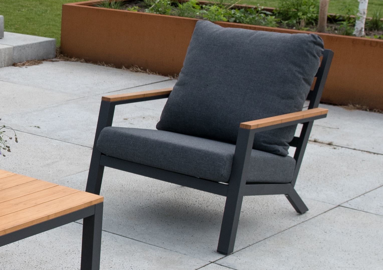 Loungestoel met grijs kussen en houtlook armleuningen; donkergrijs onderstel