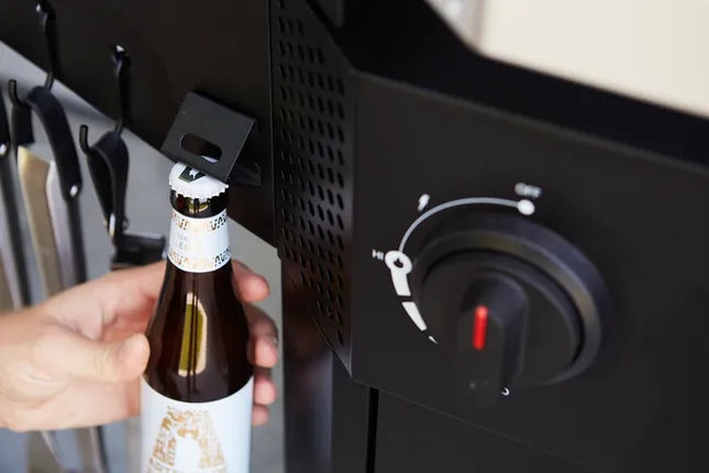 Zwarte gasbarbecue met hand die gasfles vasthoudt bij branderknop