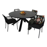 Set ronde eettafel met donkergrijs blad en zwarte stoelen, bloemkussen op stoel