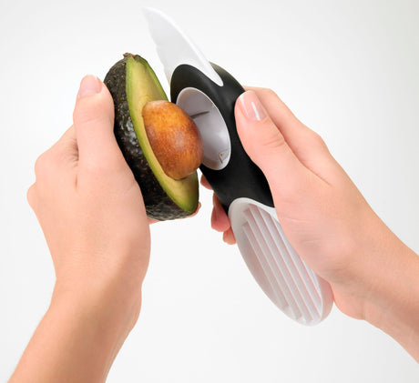 Avocadosnijder 3-in-1 in gebruik: avocado met zwarte greep en witte inzet.