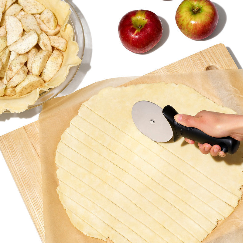 OXO-pizzasnijder met duimbeschermer, snijkop over deeglap op houten ondergrond