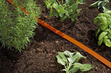 Oranje druppelslang in een beplantingsperk langs de grond