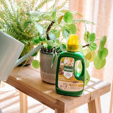 Bio kamerplantenvoeding fles 500 ml, groen met gele dop, naast kamerplant