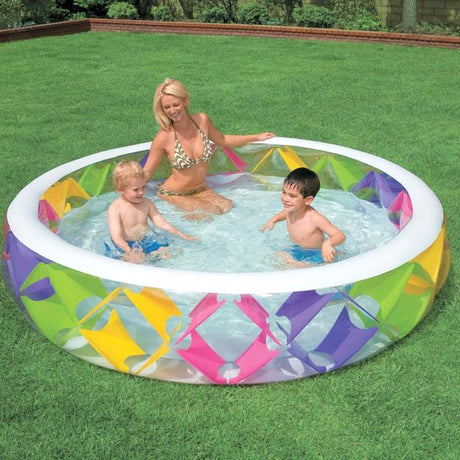 Opblaasbaar zwembad met pinwheel print gevuld met water, met spelende kinderen