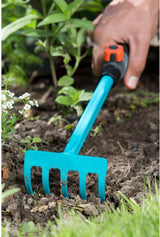 GARDENA handharkje in gebruik; teal harkkop met blauwe steel in de grond