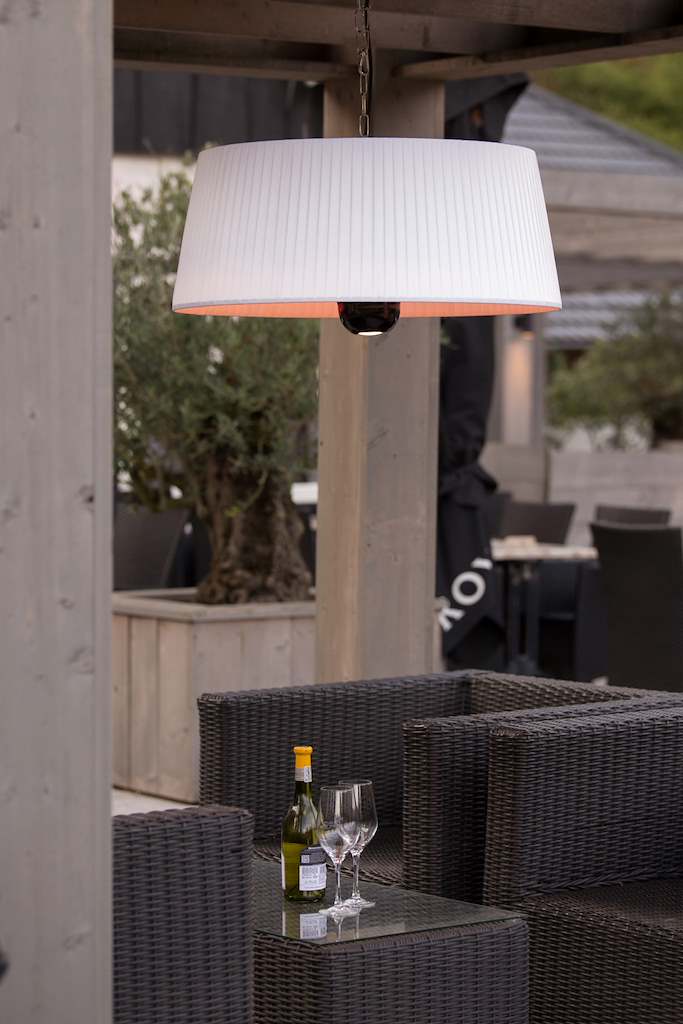 Hangende witte terrasverwarmer met ketting en lichtbron onder de lampenkap