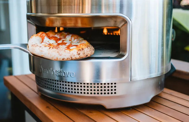 RVS pizza draaier die een pizza in een Solo Stove oven draait