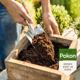 Stortende potgrond in houten plantenbak met Pokon-zak en groen etiket in beeld