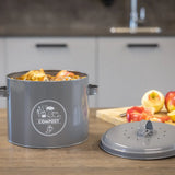 Keukencomposter antraciet met COMPOST-logo en losse bodemplaat op tafel.