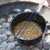 Popcornpan met gaasmandje gevuld met popcorn op open vuur