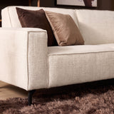 Beige stoffen bank met dikke armleuning en sierkussens; chaise rechts deel zichtbaar