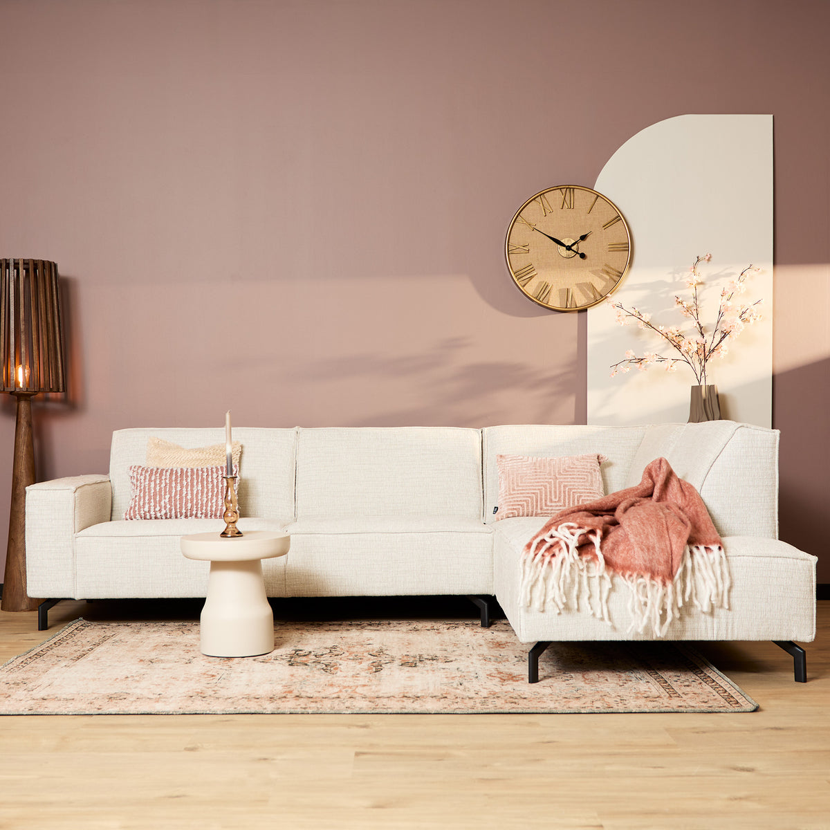 Beige hoekbank met chaise rechts, decoratieve kussens en roze plaid op de chaise