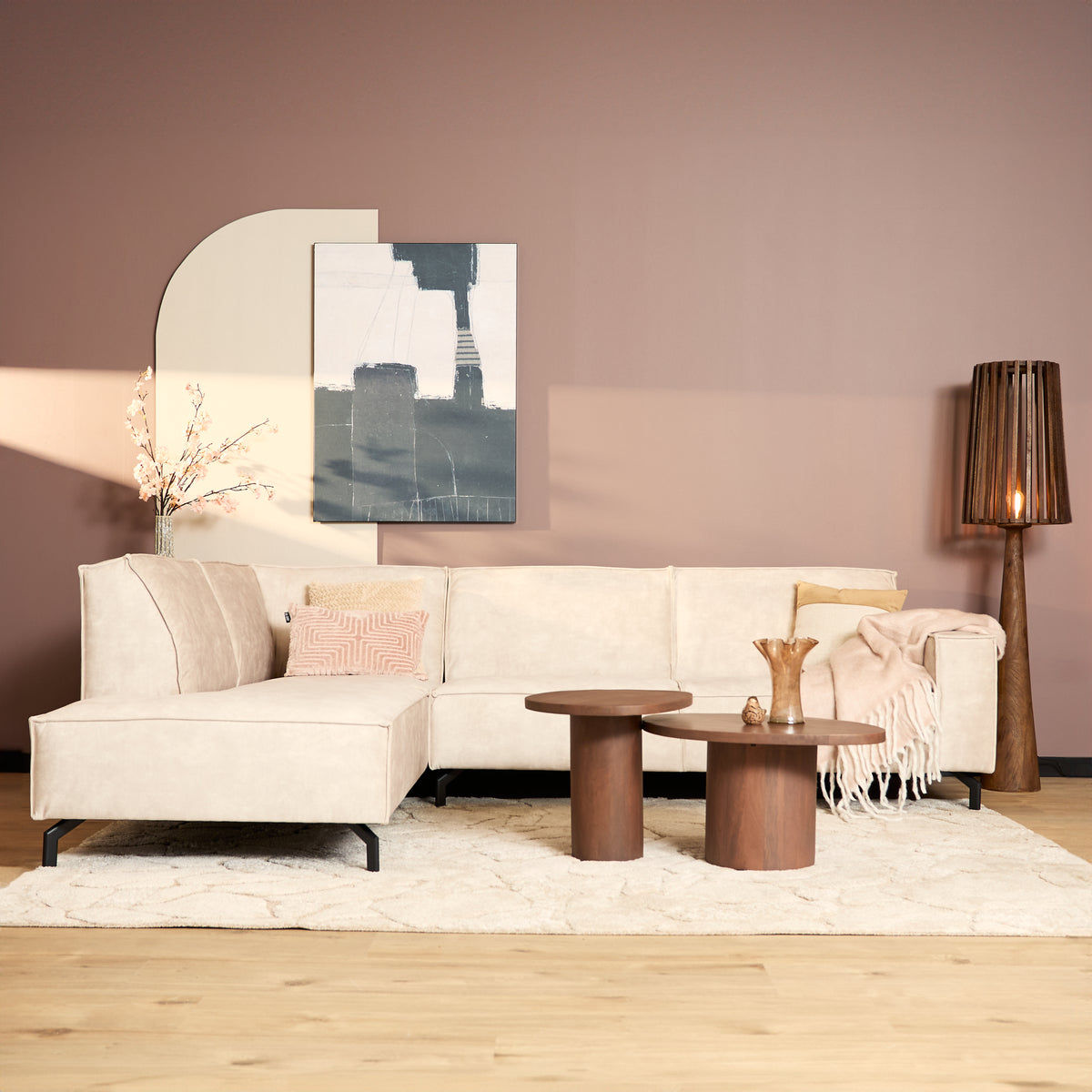 Beige fluwelen hoekbank met chaise links, lage poten en kussens op de zit