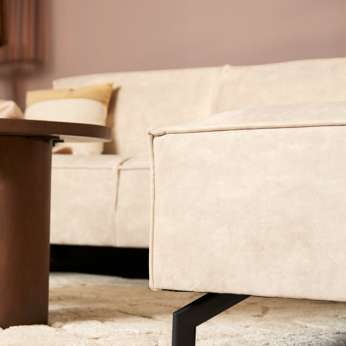 Close-up van beige fluwelen armleuning en zwarte poot onder de hoekbank