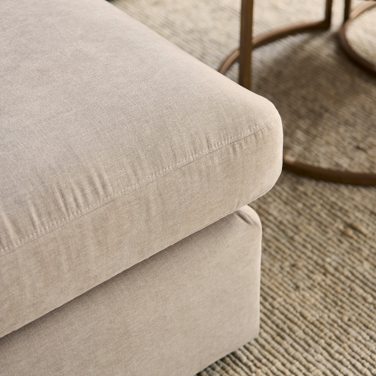 Beige bankzitting met afgeronde hoek en gladde bekleding, zichtbare naden