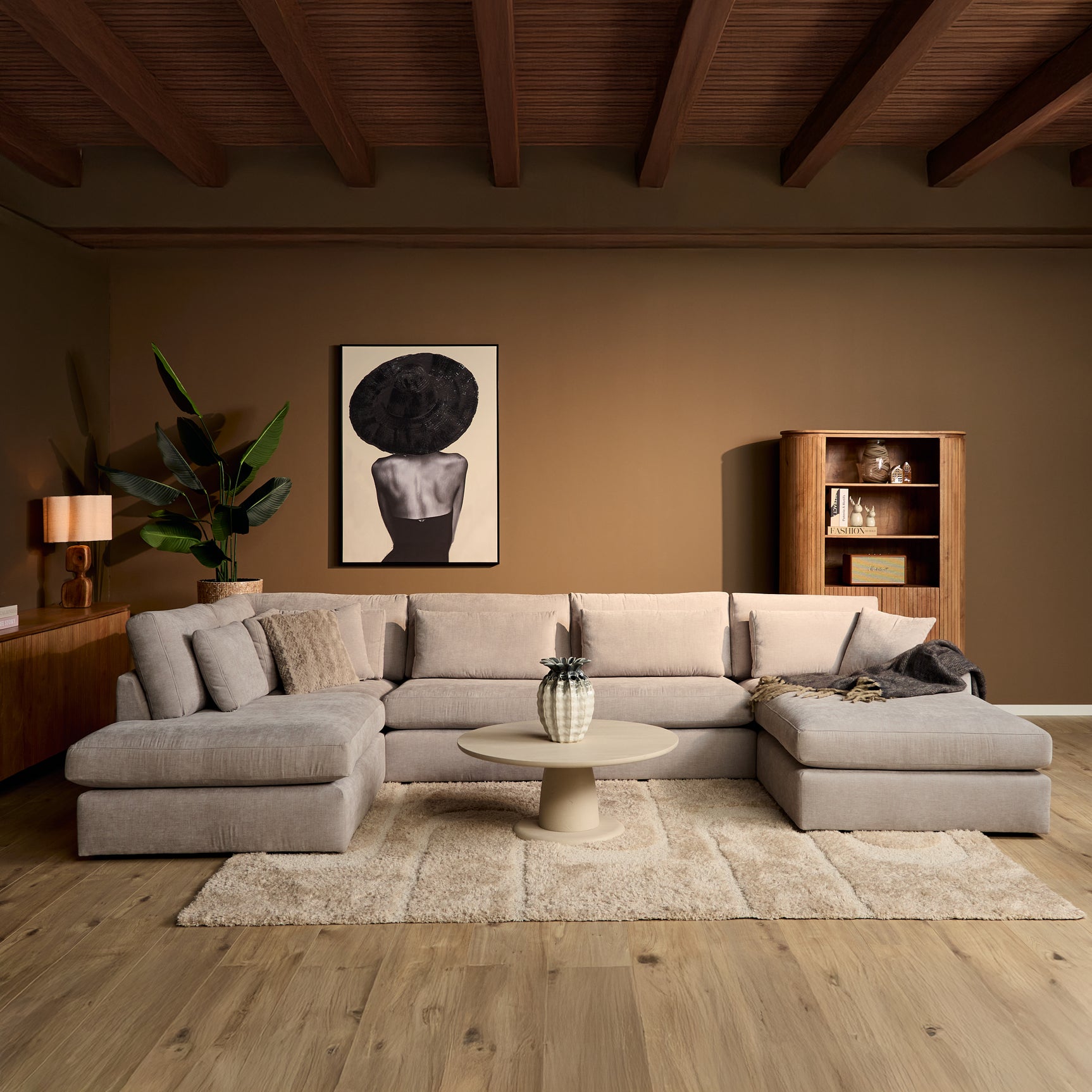 Lichtbeige U-vormige bank met losse sierkussens en brede chaise-hoek