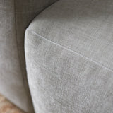 Lichtgrijze zit- en zijpaneel van chaise longue bank met strakke naden en textuur.