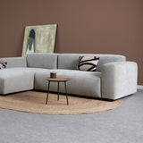 Grijze chaise longue met armleuning, sierkussens en lichtgekleurde plaid; ronde pootjes