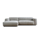 Lichtgrijze chaise longue bank met brede armleuningen en losse zittingkussens.