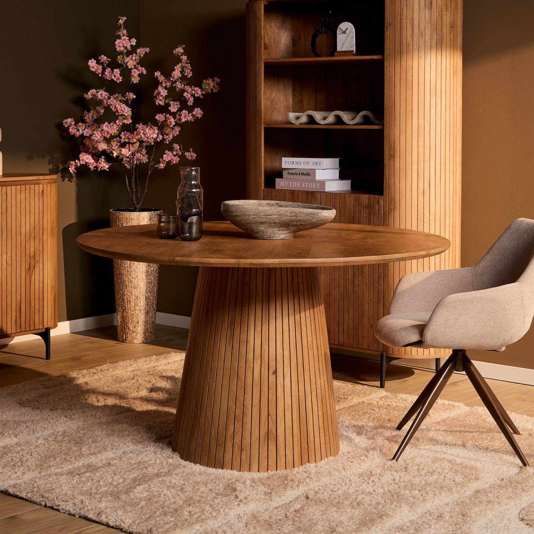 Ronde eettafel met naturel houtnerf blad en conische ribbelpoot, stoel zichtbaar