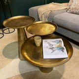 Gouden ronde salontafelset met meerdere bladen, mok en tijdschrift op het blad