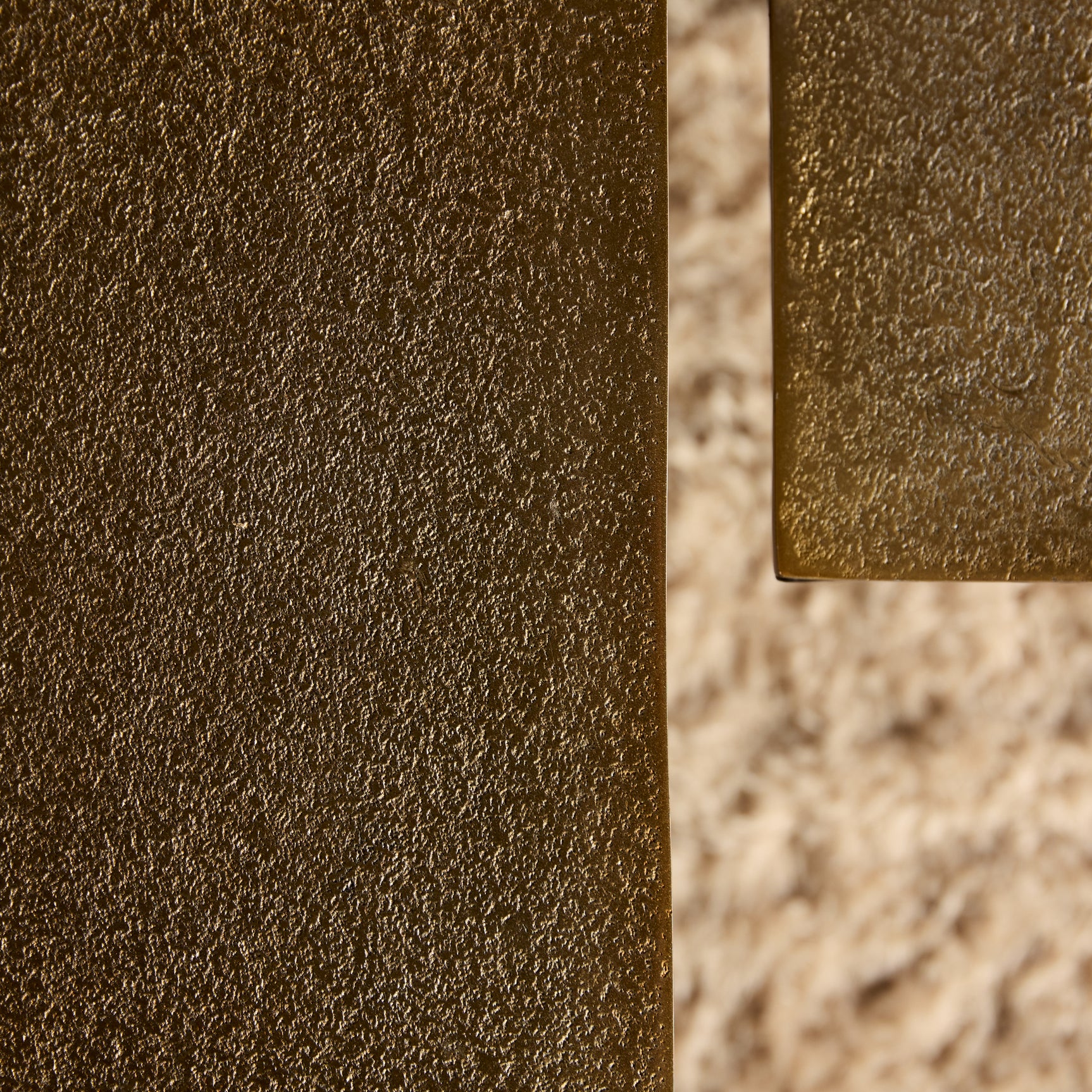 Hoekdetail van goudbruine salontafel met glanzende metalen rand en textuur