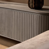 Tv-meubel zijpaneel met verticale ribbels en taupe/grijze afwerking.