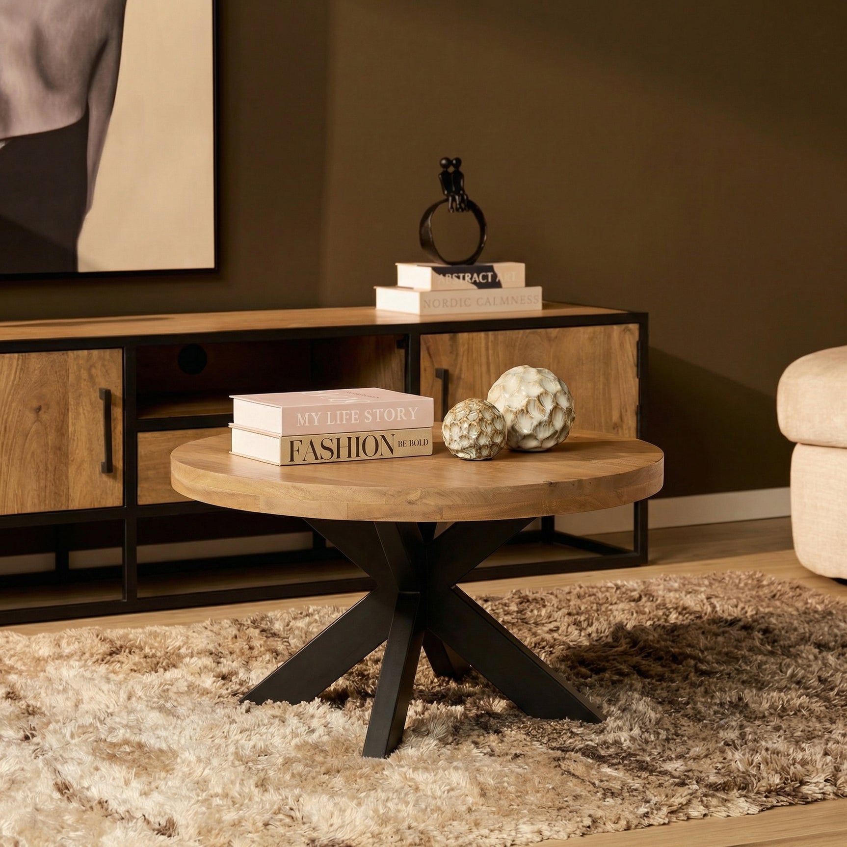 Ronde salontafel met licht houten blad en zwarte kruispoten, met decoratie
