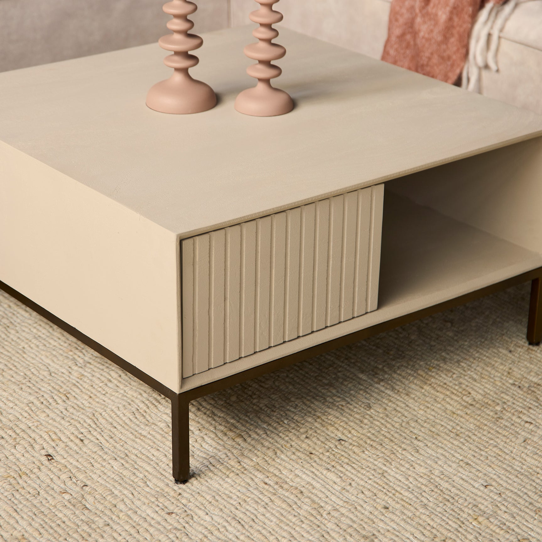 Vierkante salontafel zandkleur met open opbergvak en frontpaneel met verticale ribbels.