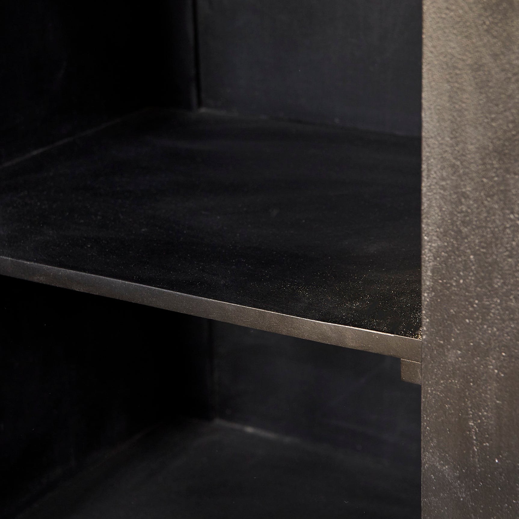 Open dressoir met zwarte binnenkant en plank, zicht op scharnieren aan de zijkant