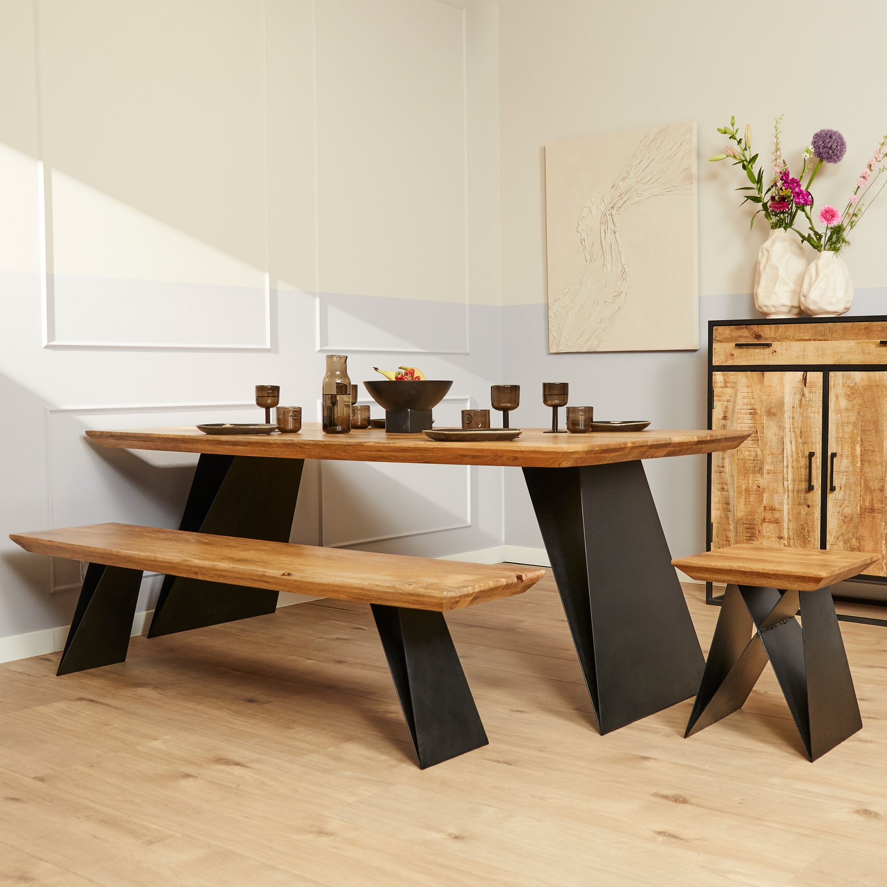 Eetkamertafel met eikenhouten blad en zwarte schuine poten, met houten bankje