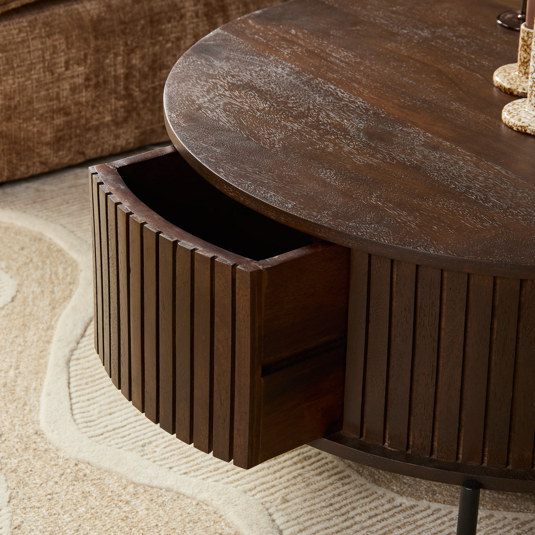 Detail van ronde salontafel: open lade onder het ronde houten blad met lamellenfront
