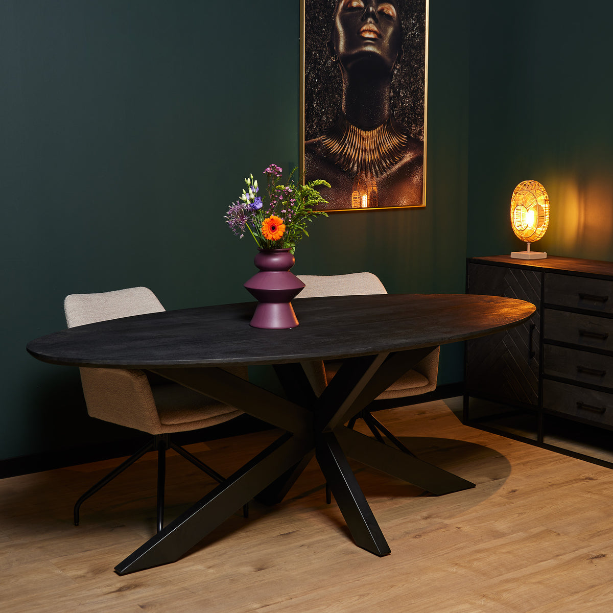 Ovale eettafel met donker houten blad en zwarte X-poot onderstel.