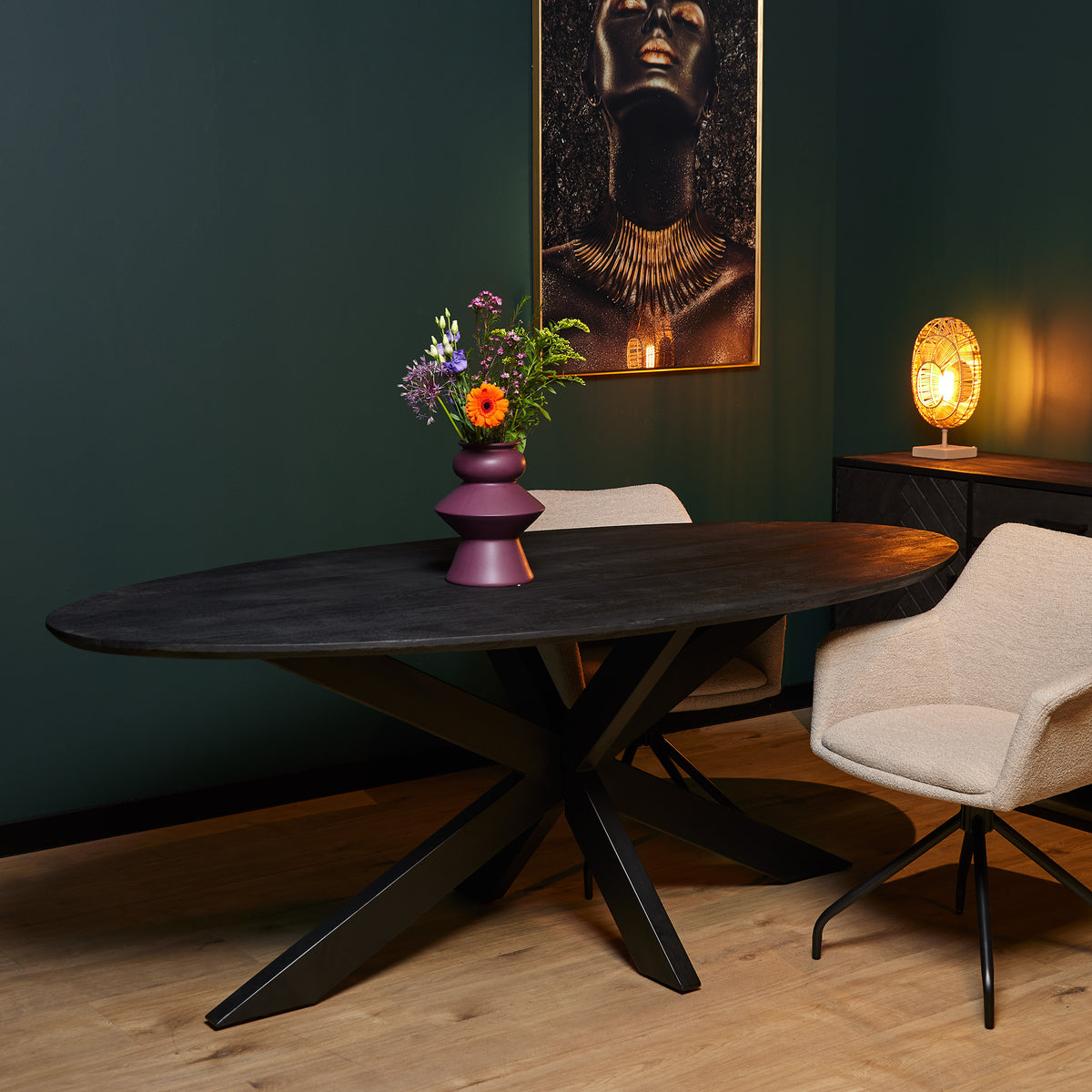 Ovale eettafel met donker houten blad en kruispoot, met beige stoelen ernaast.