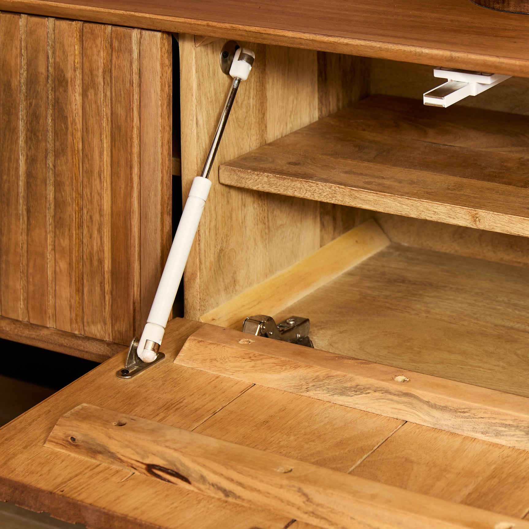 Zwevend tv-meubel met open klep, scharniermechanisme en binnenplank van naturel hout.